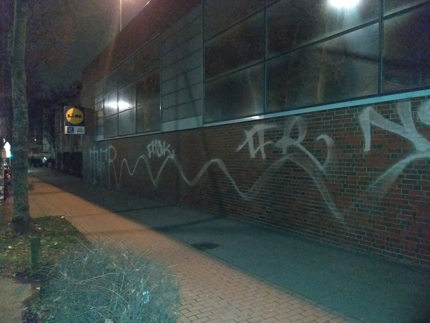 Großes, weißes Graffiti an einer Wand bei Nacht